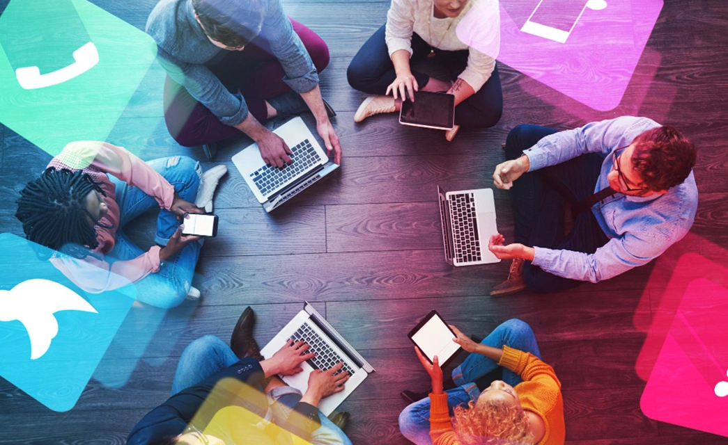 A diverse group of people collaborating on digital devices, with social media icons symbolizing the channels used in community management marketing.